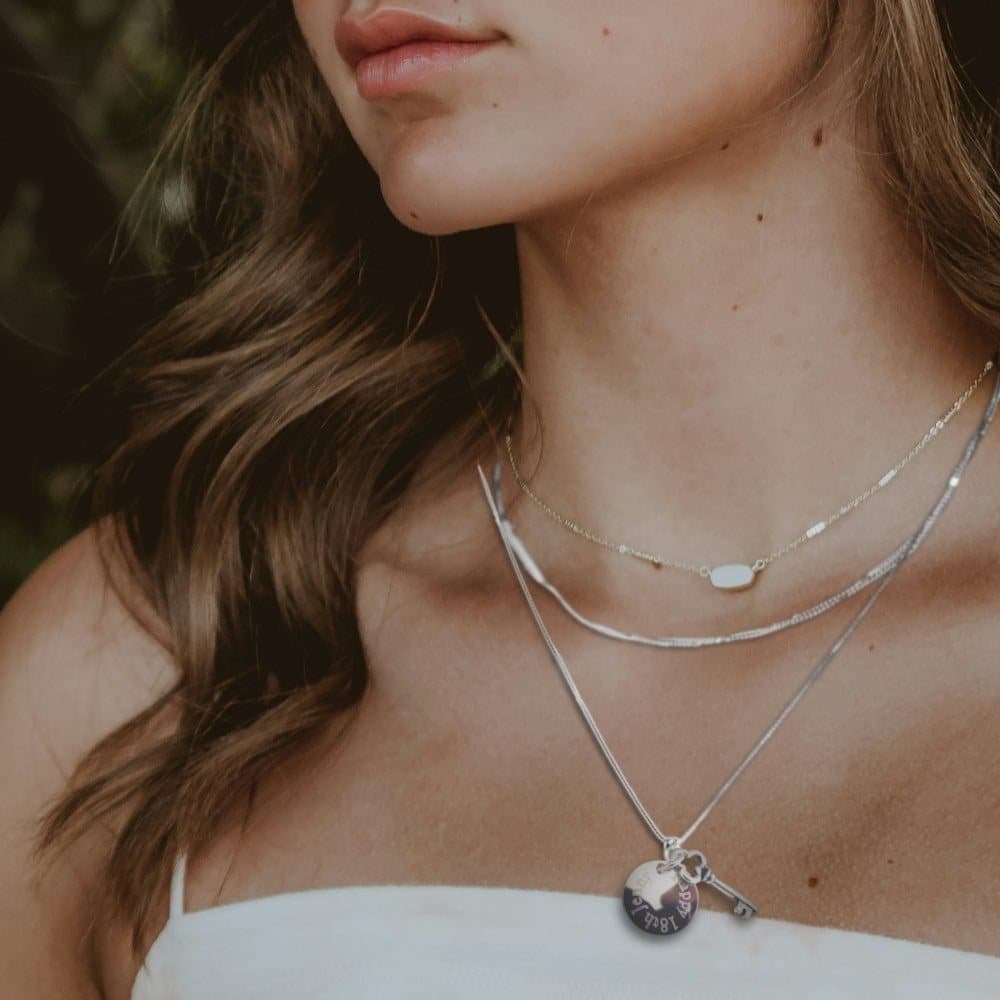 Silver key charm necklace with an engraved round charm on a silver chain