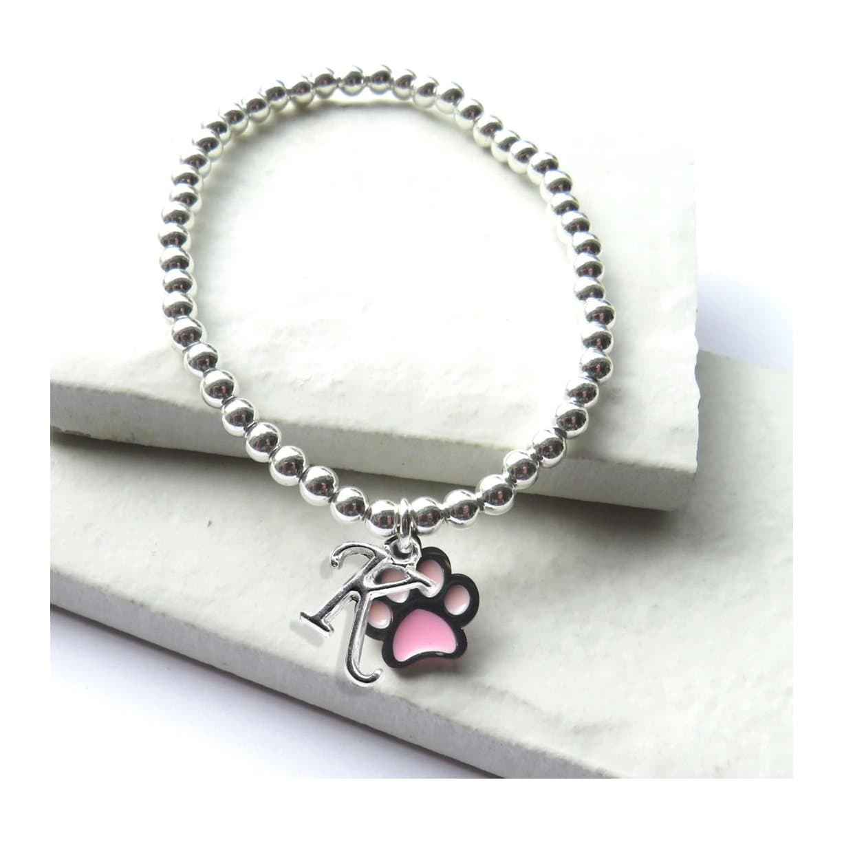 Silver beaded stretch bracelet with a pink paw charm and a silver initial