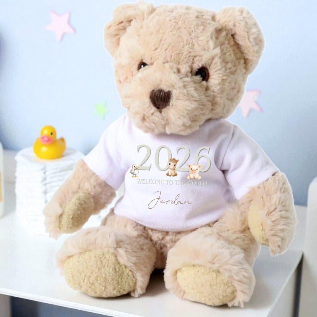 Teddy bear in a taupe T-shirt with farm animals and 2026 Welcome to the World
