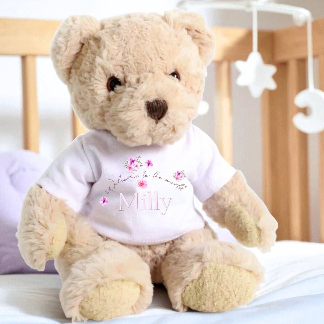 Teddy bear in a printed T-shirt with floating flowers and Welcome to the World