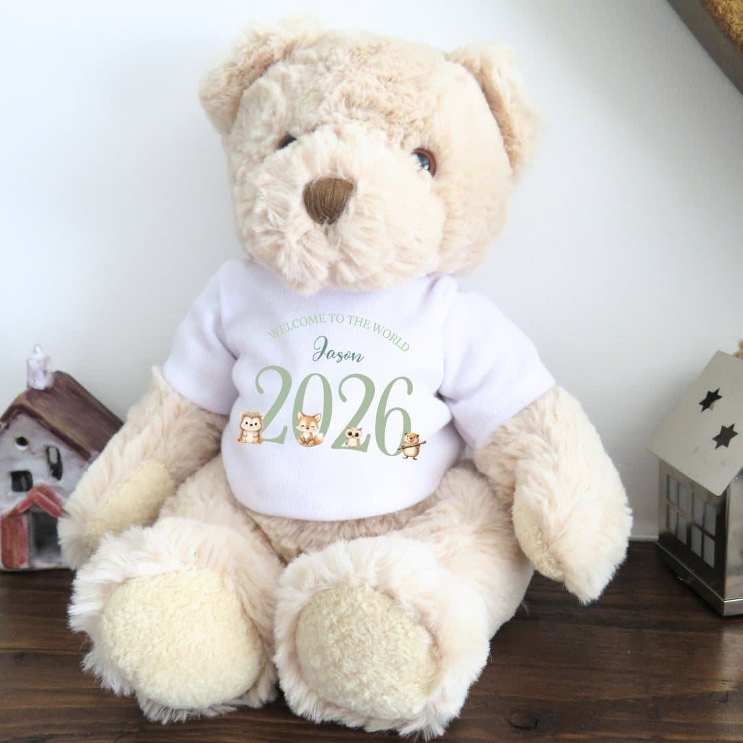 Teddy bear in a green woodland animal T-shirt with 2026 Welcome to the World design