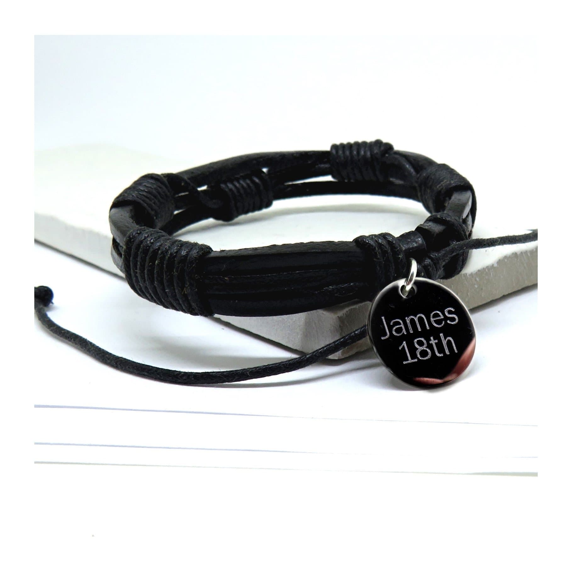 Black multi-strand leather and cord bracelet with a silver coloured engraved disc.