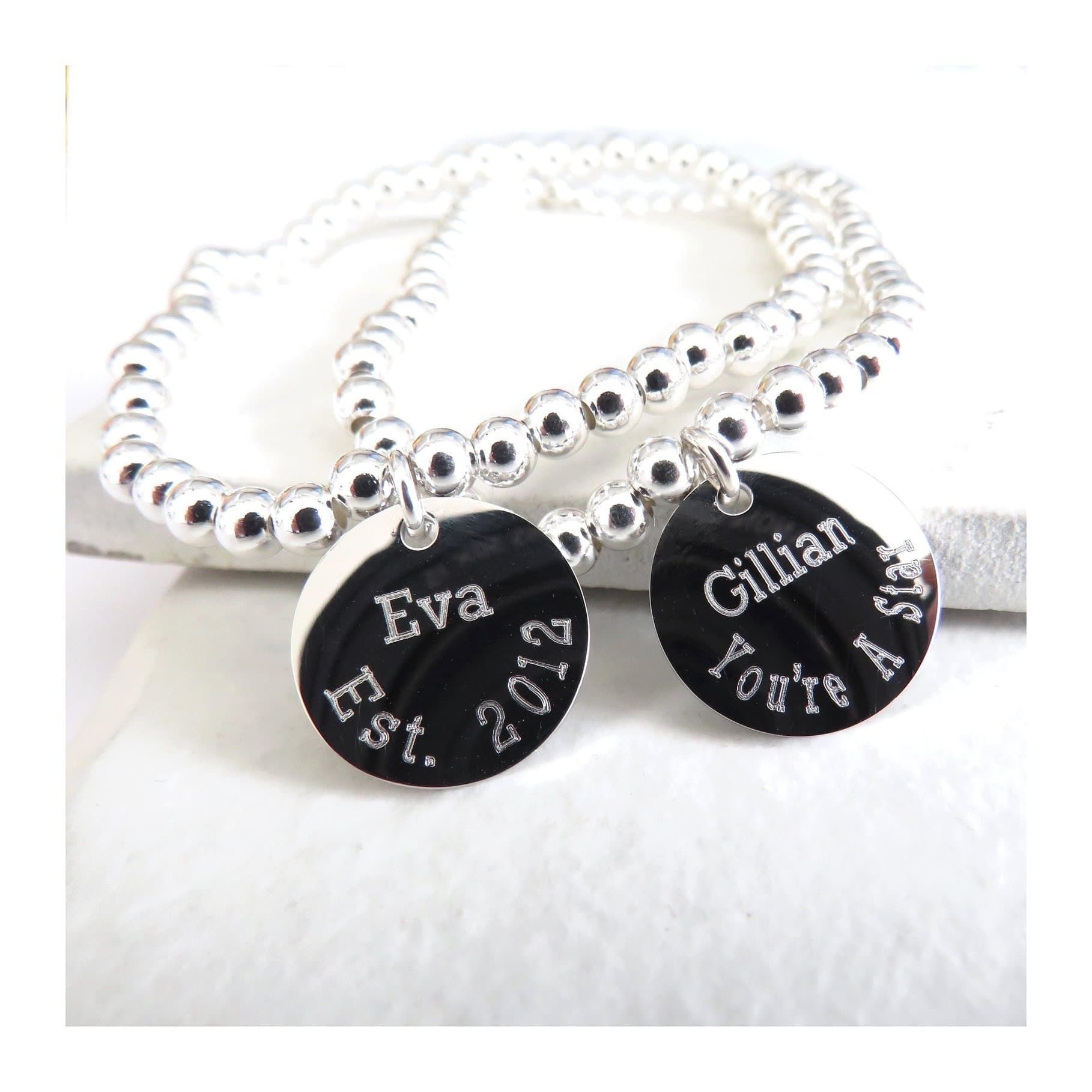 Silver coloured round charm on a beaded elasticated bracelet
