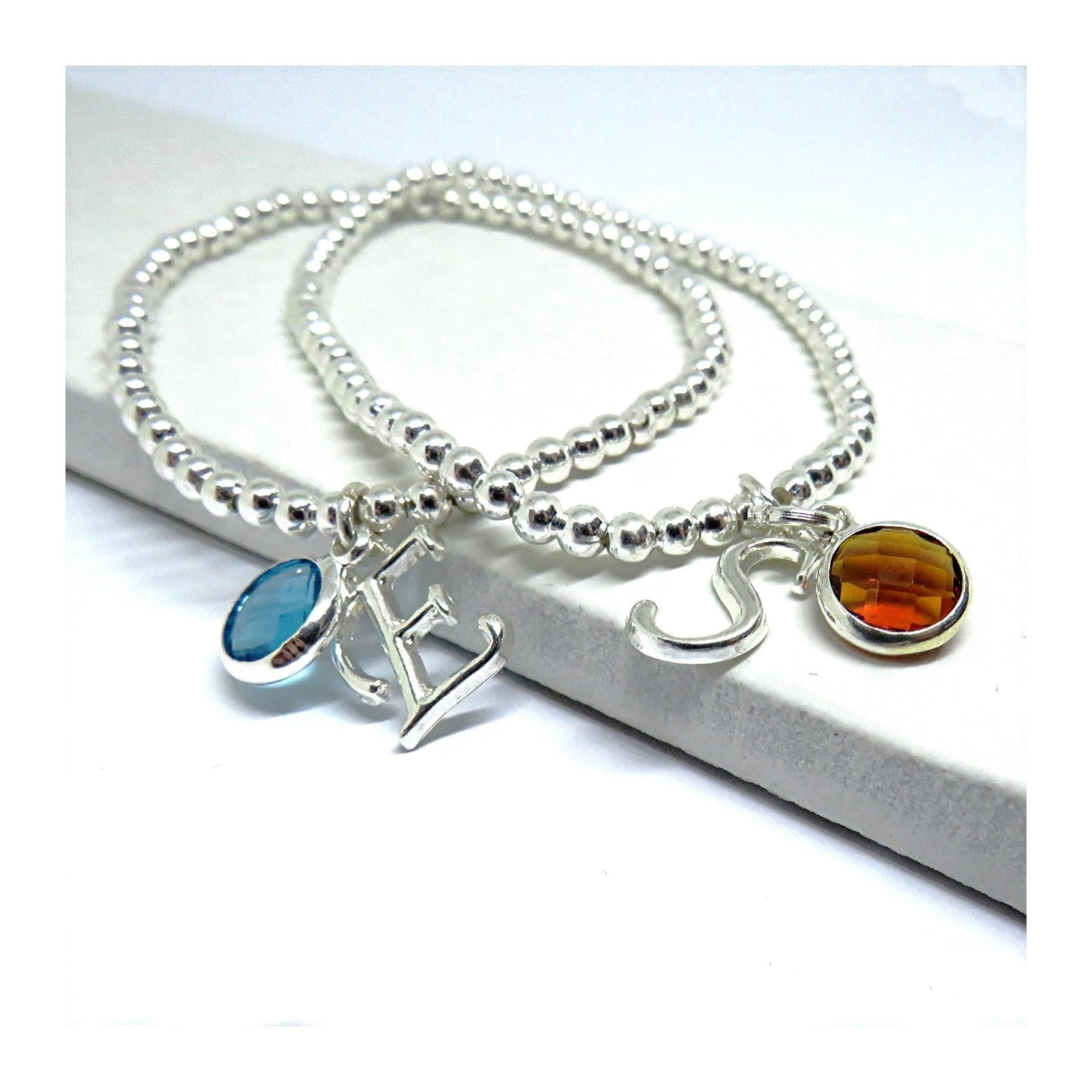 Silver stretch bracelet with a coloured birthstone and an initial charm