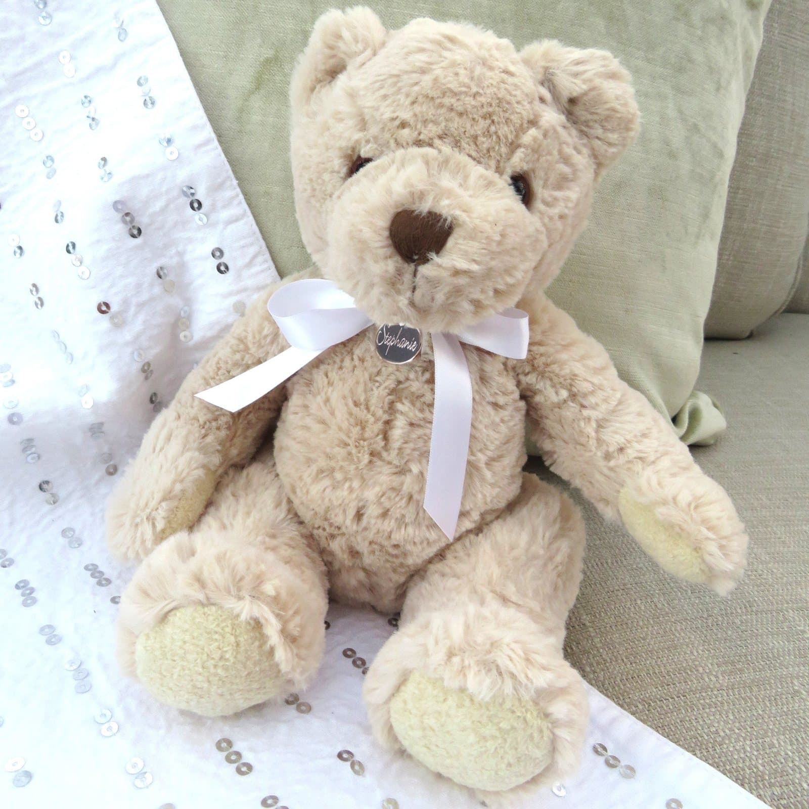 Personalised teddy bear with a stainless steel name disc on a white satin ribbon