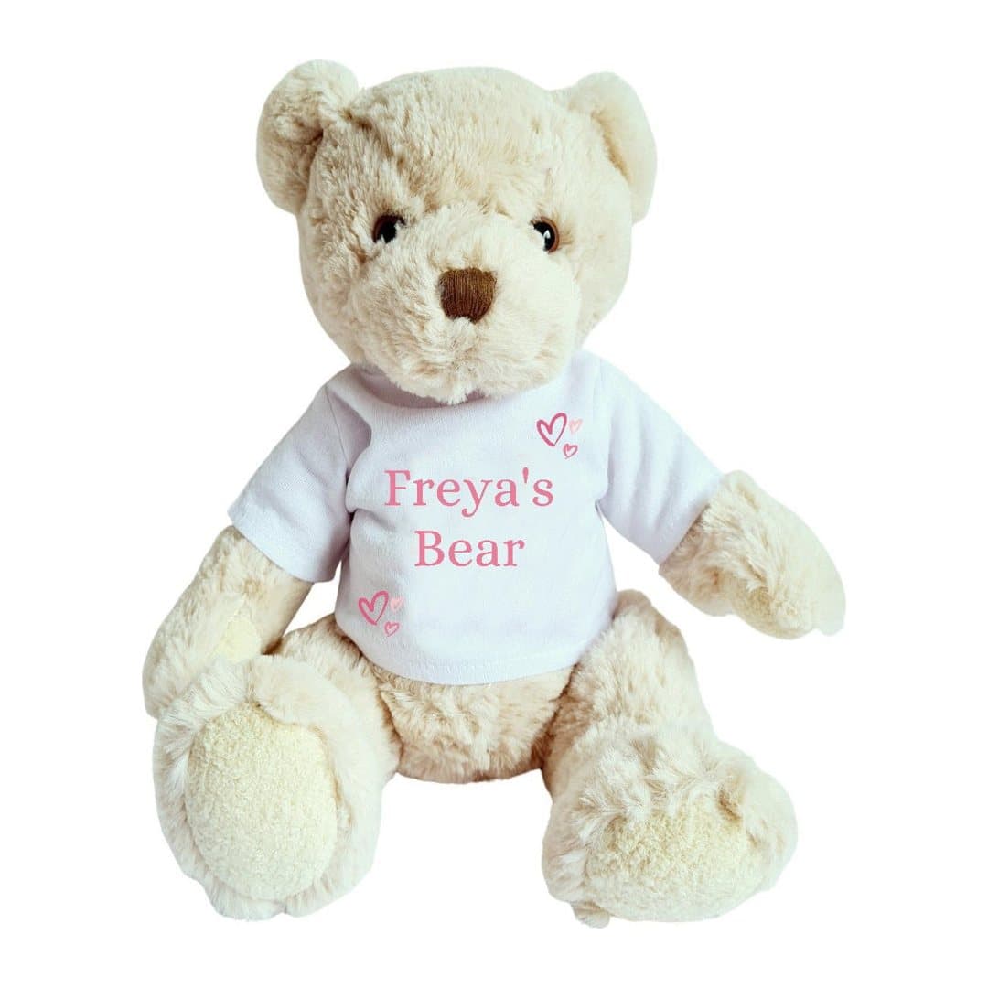 Personalised teddy bear wearing a pink T-shirt with a name and pink hearts printed on it.