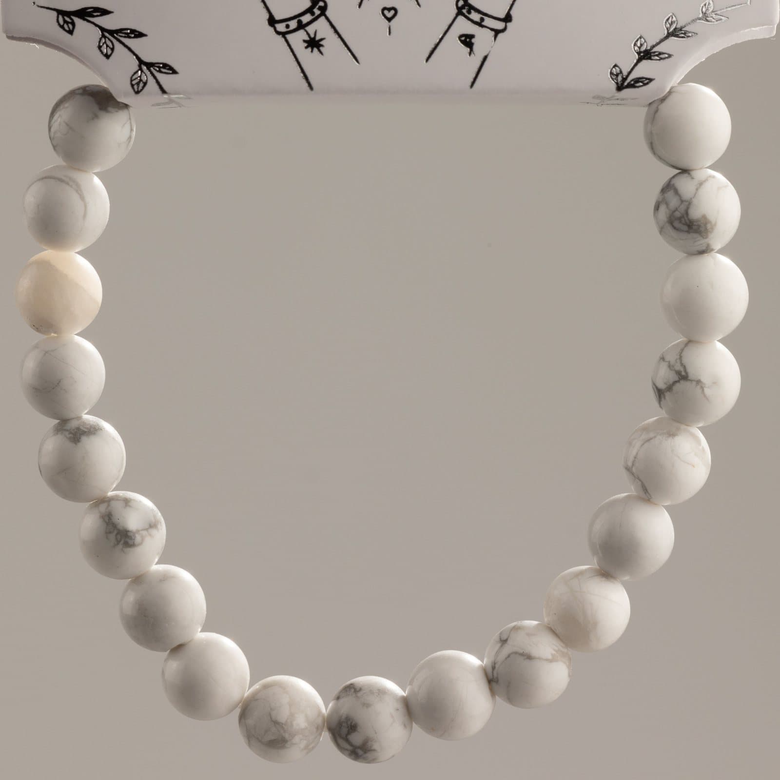 Stretch bracelet of polished white howlite beads with grey veining on a presentation card