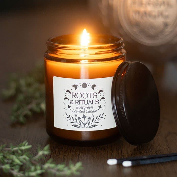 Evergreen scented candle in an amber glass jar with a Roots & Rituals label