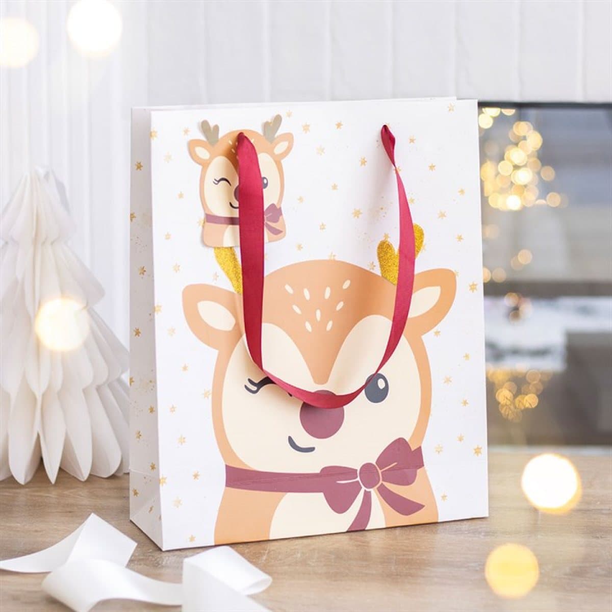 Paper Christmas gift bag with a cute reindeer, gold stars and red ribbon handles