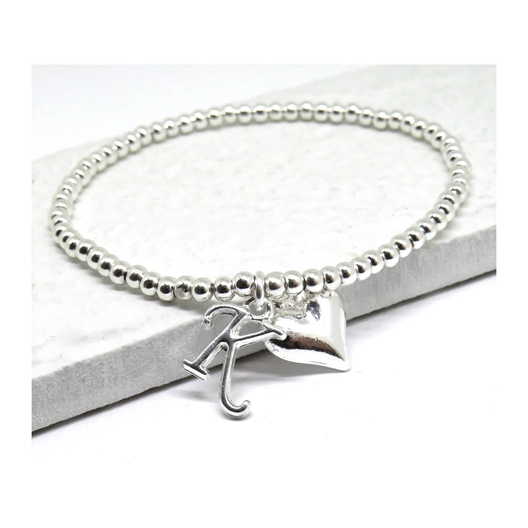 Silver stretch bracelet with a heart charm and an initial charm