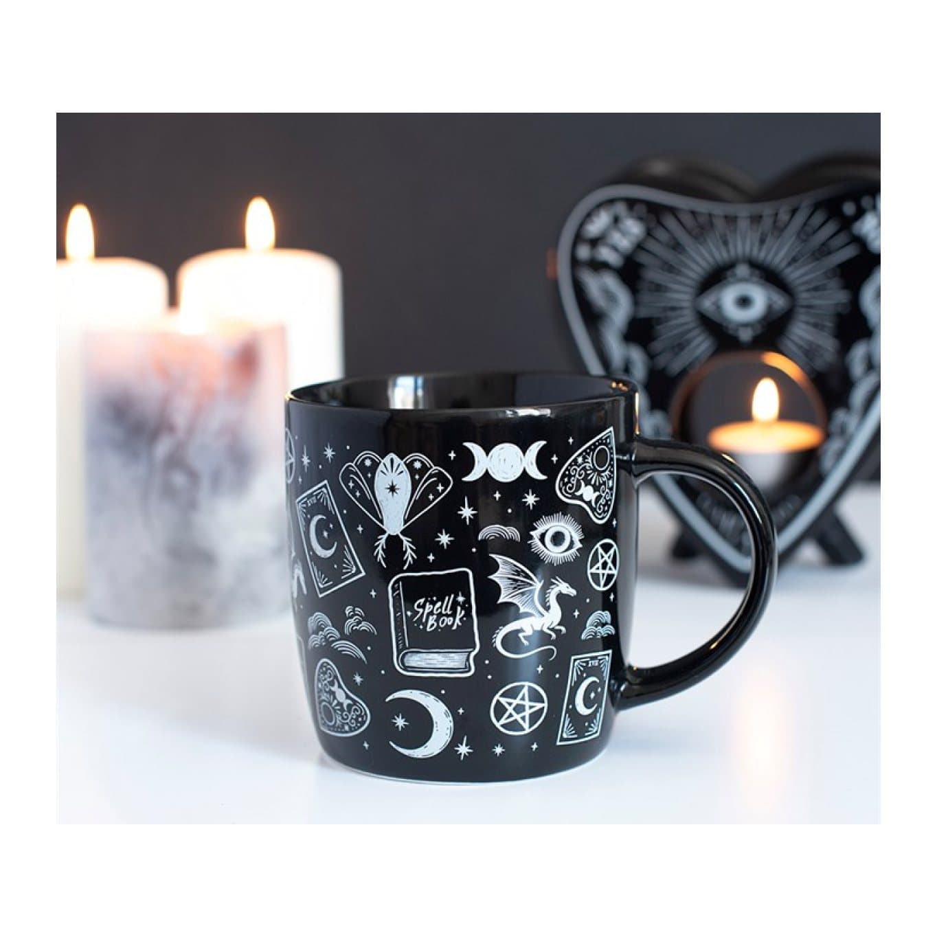 Black mug covered in spell books, moons, dragons and eyes