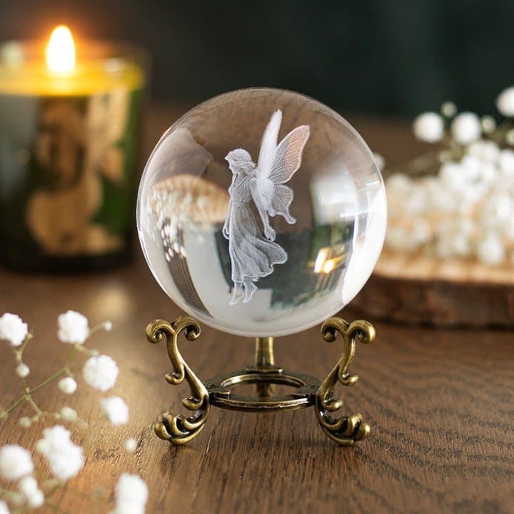 Glass crystal ball engraved with a fairy figure on an ornate antique-style stand
