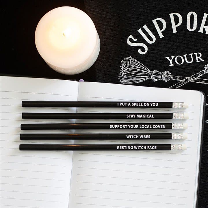 Five black witchy pencils in purple striped cardboard packaging with a window