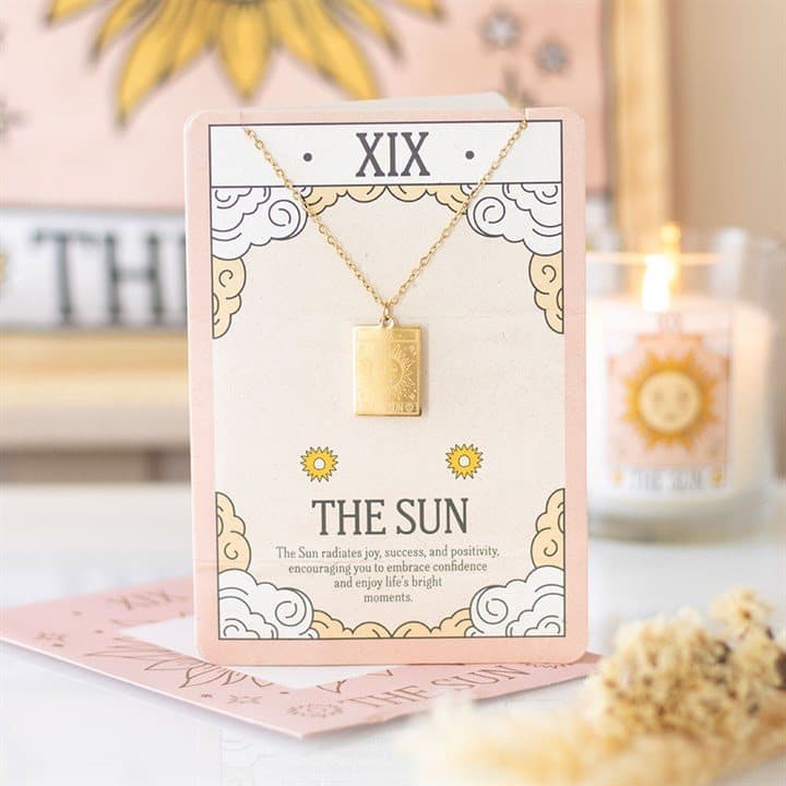 Gold-toned pendant necklace with The Sun tarot card design on a greeting card