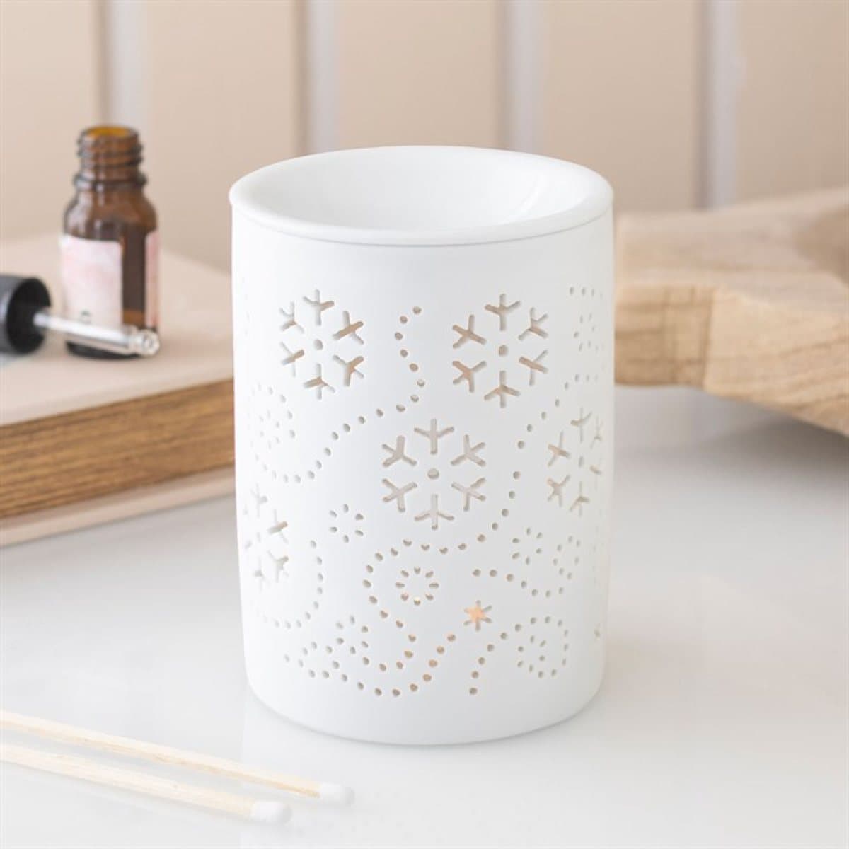 White ceramic oil burner and wax warmer with an allover snowflake cut out design